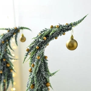 Mini snowy Christmas tree decoration with frosted green branches and gold baubles
