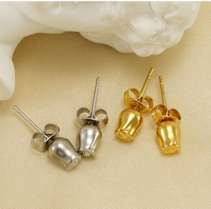 Macro shot of gold and silver rose stud earrings on fabric with white sculpture