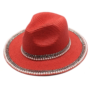 Detailed texture of red straw jazz hat with pearl and rhinestone band embellishments