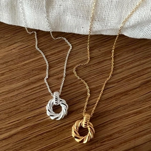 Macro detail of twisted circular pendants in gold and silver finish on textured fabric