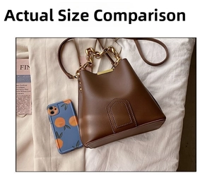 Brown leather bucket bag with gold chain strap shown next to a phone for scale reference