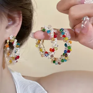 Détail de perles de cristal colorées et de petites perles blanches sur créole dorée
