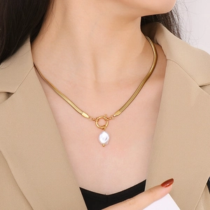 Gros plan d'un collier chaîne serpent dorée avec pendentif perle baroque étoile sur mannequin