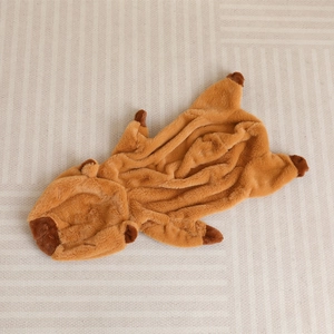 Plush brown capybara full-body onesie made of soft fleece material on a striped rug
