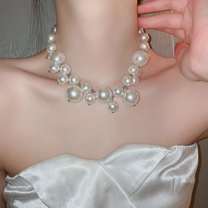 Detailed view of layered white pearl necklace worn with an elegant white dress