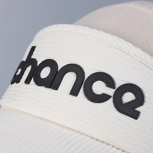 Close-up of off-white sun visor featuring textured fabric and black chance logo patch