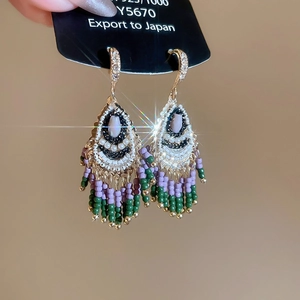 Detailed macro shot of bohemian beaded tassel earrings with crystal rhinestones on a gold base