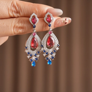 Macro shot of vintage silver earrings featuring red teardrop zircon and colorful gems