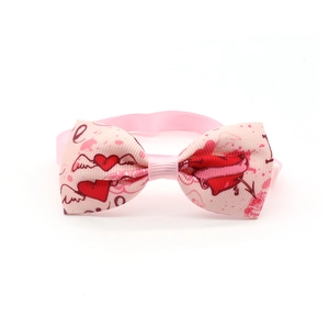 Detail of pink dog bow tie with heart and wing patterns on white background