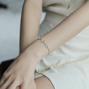 Adjustable gold chain bracelet featuring white cat-eye stone petals and tiny zircons