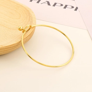 Detail of minimalist gold open bangle featuring unique ball clasp and sleek thin band
