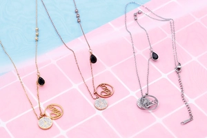 Detail of double-layered titanium steel necklaces with peace sign and letter pendants