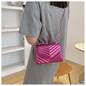 Detail of rose red patent leather chain bag with V-shaped quilted texture on shoulder