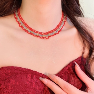 Close-up of red and gold beaded lace choker necklace on a model wearing lace dress