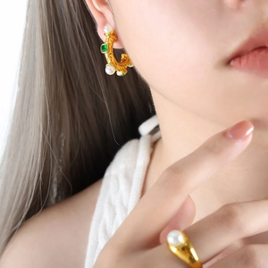 Parure de bijoux dorés rétro avec émeraude verte et perles sur un mannequin femme