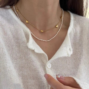 Double-layered S925 silver necklace with golden hearts and pearls worn by a model