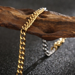 Two-tone gold and silver Cuban link chain bracelet displayed on rustic wood