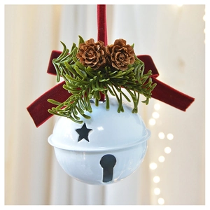 Close-up of white metal bell with red velvet bow, pine cones, and festive greenery detail
