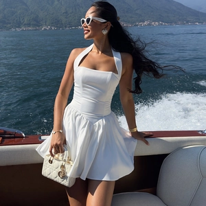 Détail d'une mini robe blanche dos nu avec jupe trapèze plissée au bord d'un lac en plein air