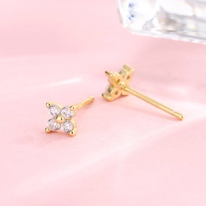 Macro detail of gold-plated four-leaf clover earrings with sparkling cubic zirconia crystals