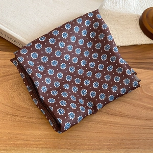 Detail of silk-like scarf necklace with blue floral print on coffee brown fabric