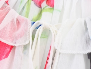 Détail de la blouse en mousseline fleurie avec tulipes rouges et liens blancs au col