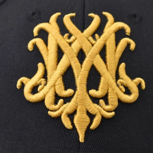 Macro shot of 3D gold embroidery on black cotton fabric showing intricate luxury details