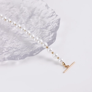 Detail of elegant white pearl bracelet featuring gold toggle clasp and bead accents