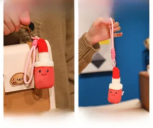Detail of cute lipstick plush keychain with smile embroidery on a beige handbag