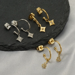 Detail of star and snake charms in gold and silver finish on gray stone background