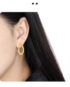 Close-up of golden S925 sterling silver twisted teardrop earrings on a female ear