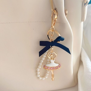 Detail of ballet girl keychain with pink rhinestones, blue bow and pearl chain on bag
