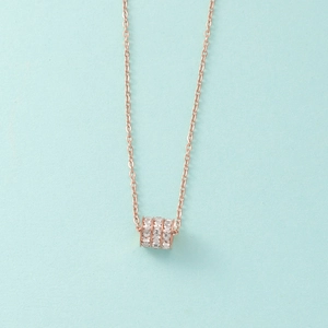 Close-up of rose gold cylinder pendant featuring triple rows of shimmering crystals
