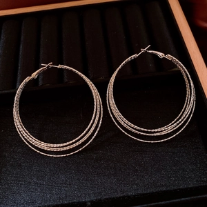 Detail of gold multi-layered textured hoop earrings displayed in a black velvet jewelry box
