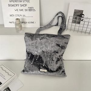 Detail of grey velvet tote bag featuring white embroidered lines and pearl embellishments