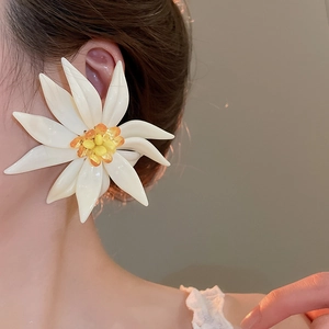 Detail showing oversized white resin flower earrings with yellow beaded stamen on model