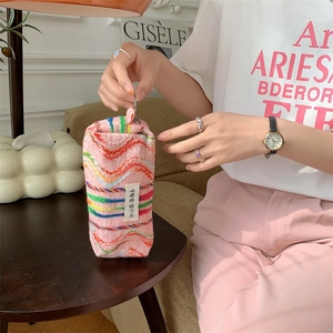 Détail d'une trousse en tricot arc-en-ciel avec base rose et texture d'étiquette