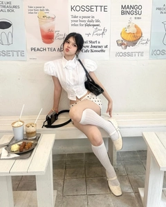 Polka dot mini skirt and puff sleeve polo top styled in a cozy cafe setting