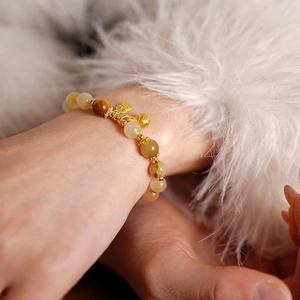 Retro citrine beaded bracelet with gold Fu pendant and bell on a white fur cuff