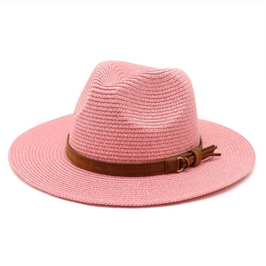 Detailed texture of pink straw sun hat with brown decorative band and gold metal ring