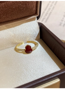 Gros plan d'une bague dorée avec gourde en émail rouge et cristaux étincelants