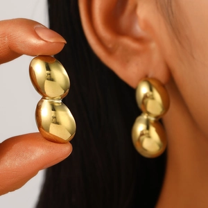 Detailed macro shot of high-polished gold geometric teardrop earrings with a mirror finish