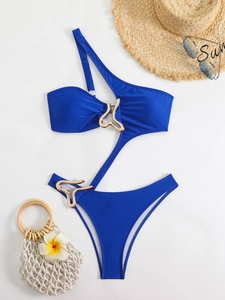 Detail of navy one-shoulder swimsuit with gold hollow-out ring and summer accessories