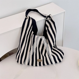 Détail d'un sac cabas en toile à rayures avec bordure en dentelle et plaque métallique
