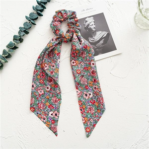 Detailed macro view of floral print scrunchie with long ribbons on artistic white backdrop