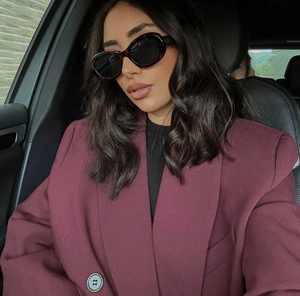 Dettaglio di un blazer bordeaux doppiopetto con occhiali da sole in un'auto di lusso