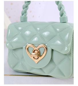 Detail of mint green jelly mini bag featuring diamond quilt pattern and gold heart lock