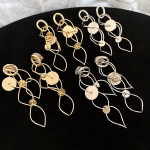 Detailed view of gold and silver metallic geometric long earrings on a black velvet display
