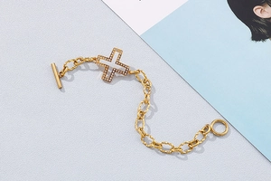 Detailed view of a gold cross bracelet with white zircon pavé and functional OT toggle clasp
