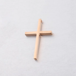 Macro detail of rose gold stainless steel cross pendant with a mirror finish and hanging hole